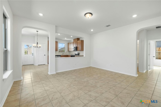 unfurnished living room featuring light tile patterned flooring and a chandelier