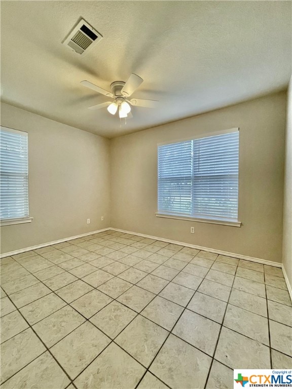 tiled empty room with a textured ceiling and ceiling fan