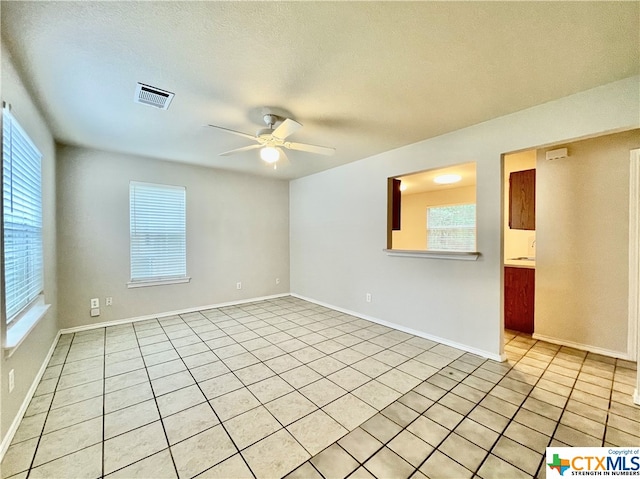 unfurnished room with ceiling fan, a textured ceiling, and light tile patterned floors