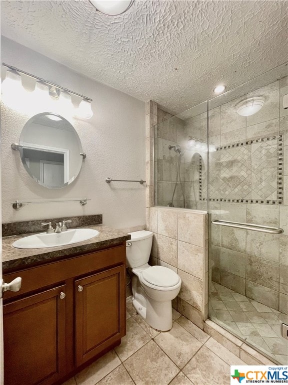 bathroom with vanity, a textured ceiling, tile patterned floors, and a shower with shower door