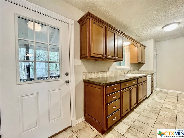 kitchen featuring dishwasher, a textured ceiling, sink, and light tile patterned floors