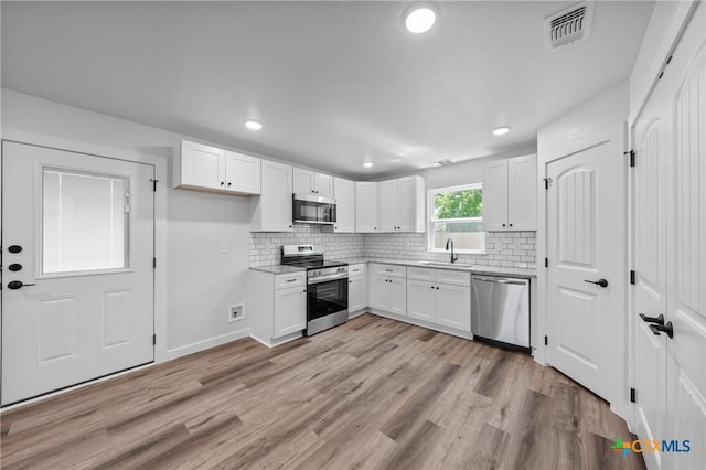 616 S 24th St, Temple, TX 76501 - kitchen with stainless steel appliances, white cabinetry, light wood-style flooring, decorative backsplash, and recessed lighting