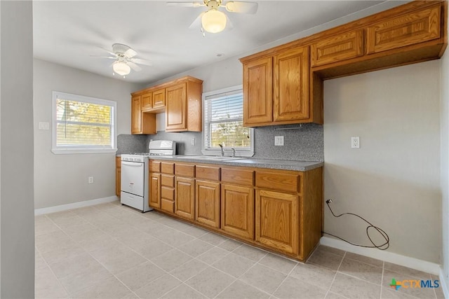 kitchen featuring backsplash, sink, a healthy amount of sunlight, and white stove