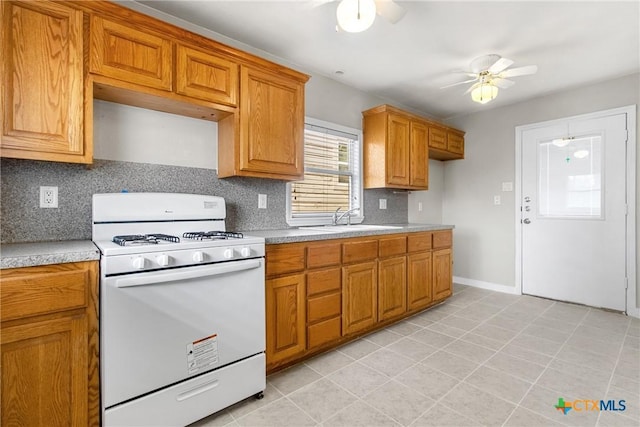 kitchen with backsplash, ceiling fan, white gas stove, and sink