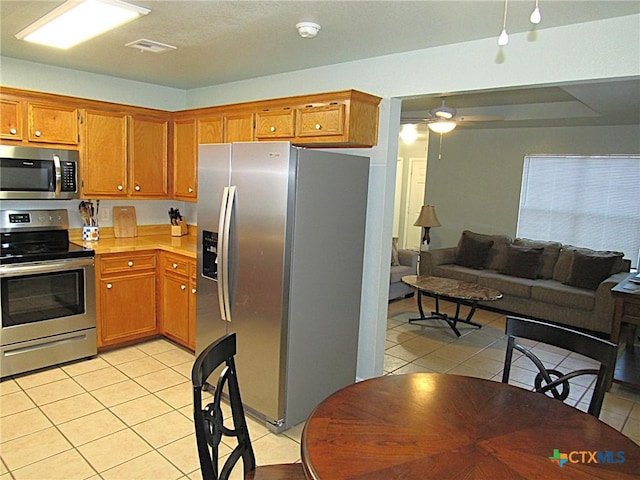 1104 N Blair St, Belton, TX 76513 - kitchen with stainless steel appliances, light tile patterned floors, brown cabinetry, and light countertops