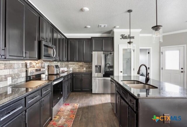 1606 Fiddle Wood Way, Temple, TX 76502 - kitchen featuring appliances with stainless steel finishes, crown molding, dark stone counters, an island with sink, and hardwood / wood-style flooring