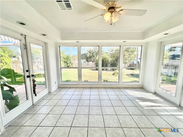 unfurnished sunroom with plenty of natural light, ceiling fan, and a raised ceiling