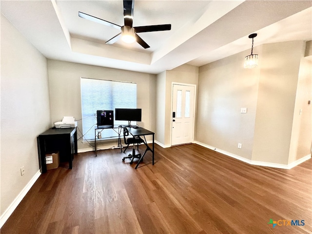 office area with hardwood / wood-style flooring, ceiling fan with notable chandelier, and a tray ceiling