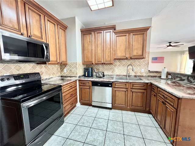 kitchen with appliances with stainless steel finishes, sink, backsplash, and light tile patterned flooring