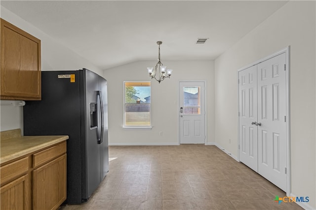 kitchen featuring lofted ceiling, hanging light fixtures, black fridge with ice dispenser, and a notable chandelier