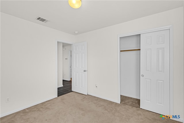 unfurnished bedroom with light carpet and a closet