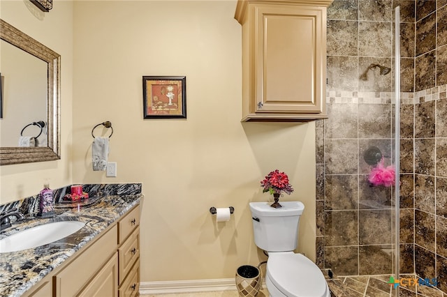 bathroom featuring toilet, vanity, and a tile shower