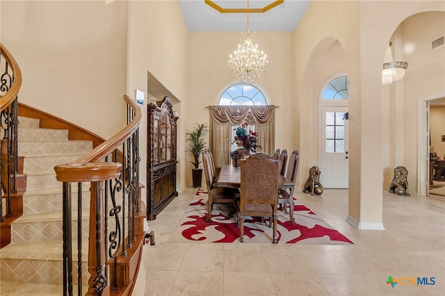 tiled dining room featuring a towering ceiling and a notable chandelier