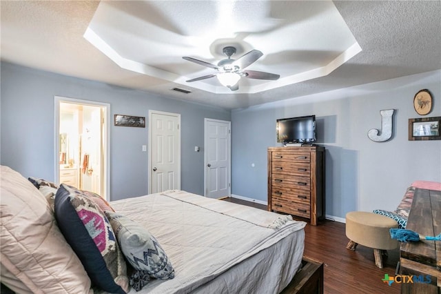 bedroom with ceiling fan, dark wood-type flooring, a textured ceiling, and a tray ceiling