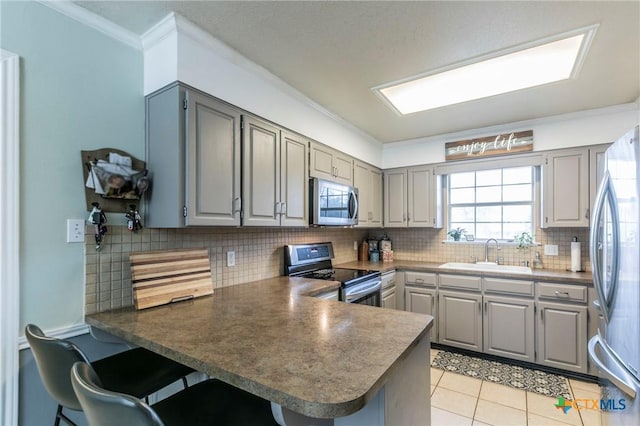 kitchen with sink, crown molding, gray cabinetry, stainless steel appliances, and kitchen peninsula