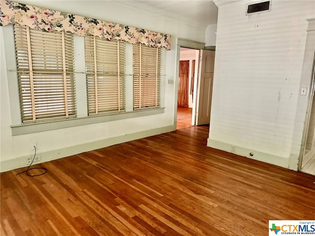 spare room featuring hardwood / wood-style floors and crown molding