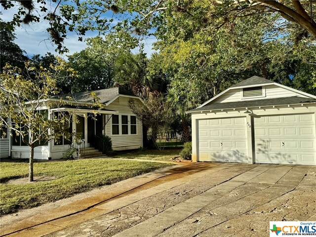 view of front of home with a front lawn, a garage, and an outbuilding