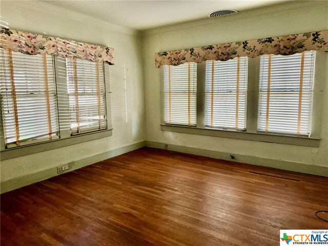 spare room featuring dark hardwood / wood-style floors and crown molding