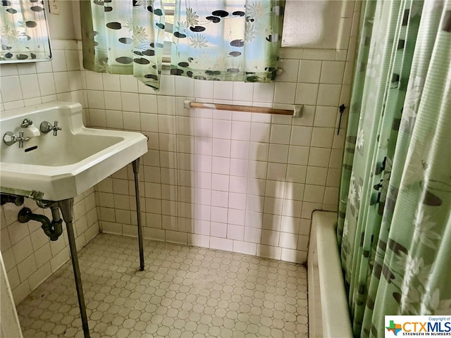 bathroom featuring tile walls, sink, and shower / tub combo with curtain