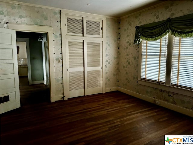 unfurnished bedroom with dark hardwood / wood-style floors, a closet, and ornamental molding