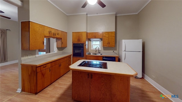 kitchen featuring ceiling fan, sink, a center island, black appliances, and ornamental molding