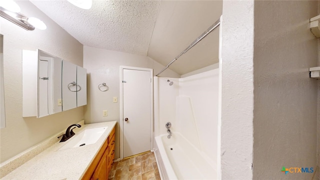 bathroom with vanity, washtub / shower combination, a textured ceiling, and lofted ceiling