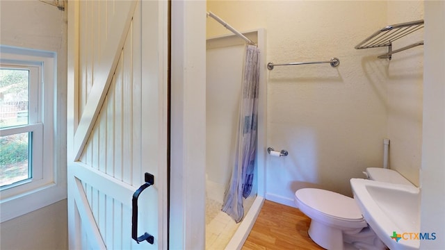 bathroom with curtained shower, toilet, and hardwood / wood-style flooring