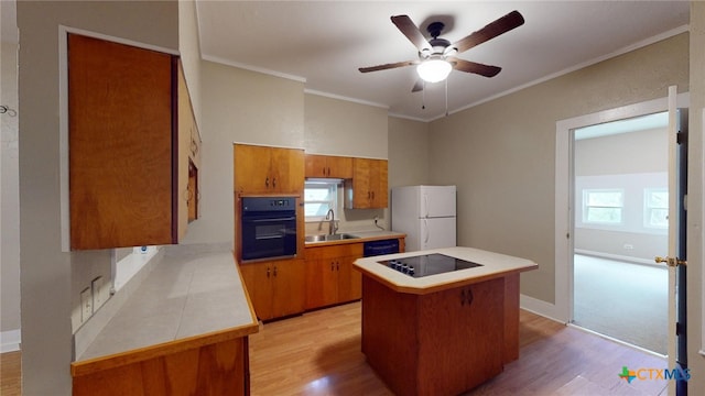 kitchen with a center island, black appliances, sink, light wood-type flooring, and ornamental molding