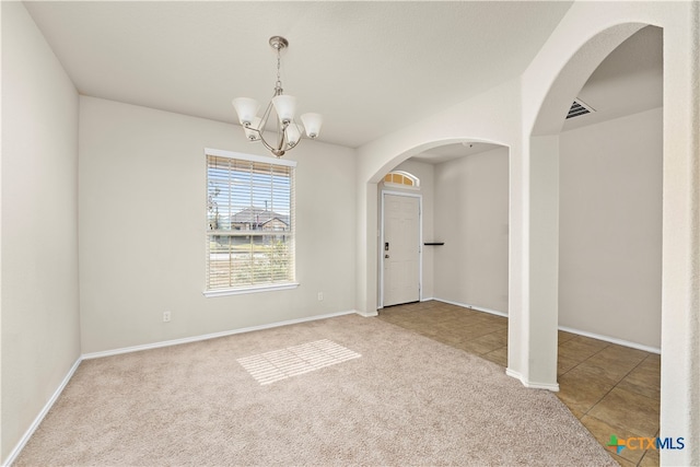 empty room with carpet flooring and a chandelier