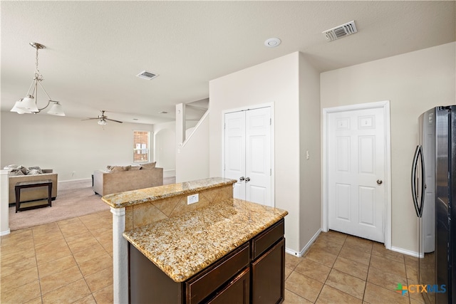 kitchen featuring pendant lighting, a center island, ceiling fan, a textured ceiling, and dark brown cabinetry