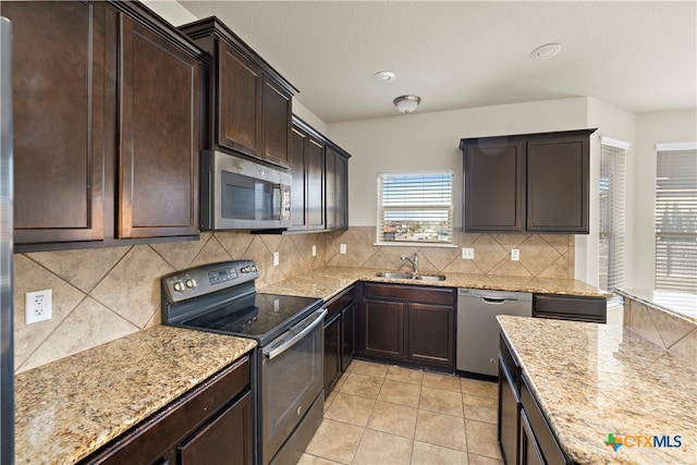 kitchen featuring sink, light stone countertops, tasteful backsplash, light tile patterned flooring, and stainless steel appliances