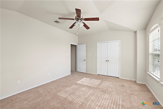 unfurnished bedroom with ceiling fan, a closet, light carpet, and vaulted ceiling