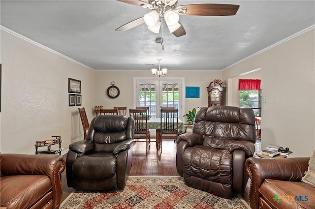 living room featuring ornamental molding, ceiling fan with notable chandelier, and wood finished floors