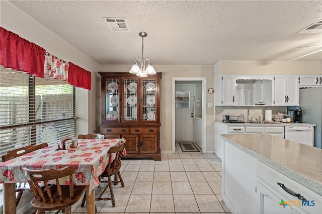 dining space featuring an inviting chandelier, light tile patterned flooring, a textured ceiling, and visible vents