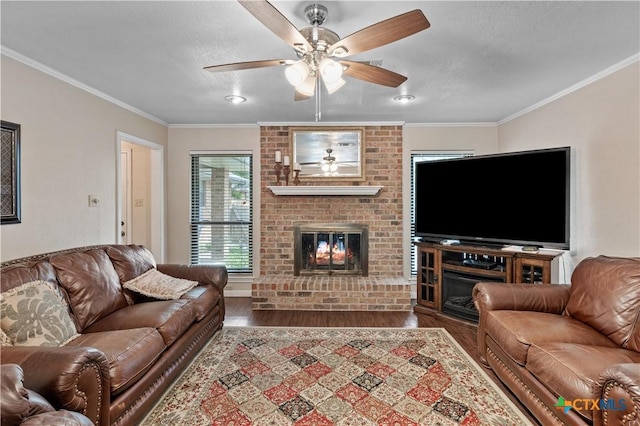 living room with crown molding, dark wood-style flooring, a brick fireplace, and ceiling fan