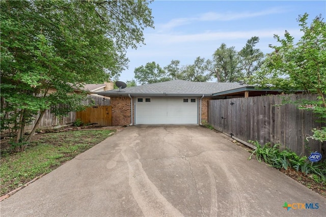garage featuring fence and aphalt driveway