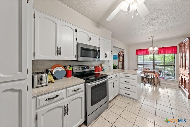 kitchen featuring a textured ceiling, appliances with stainless steel finishes, light countertops, white cabinets, and a peninsula