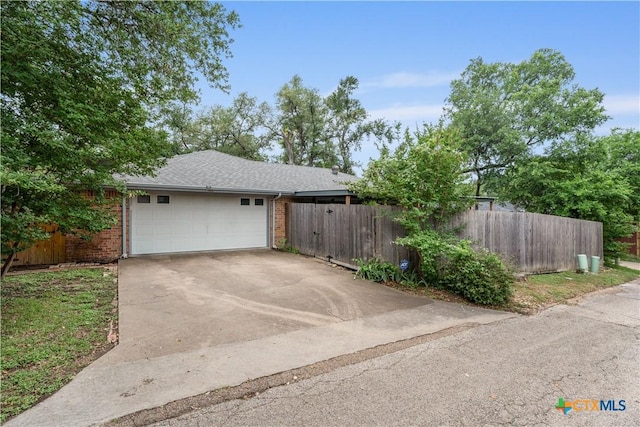 garage featuring fence and concrete driveway