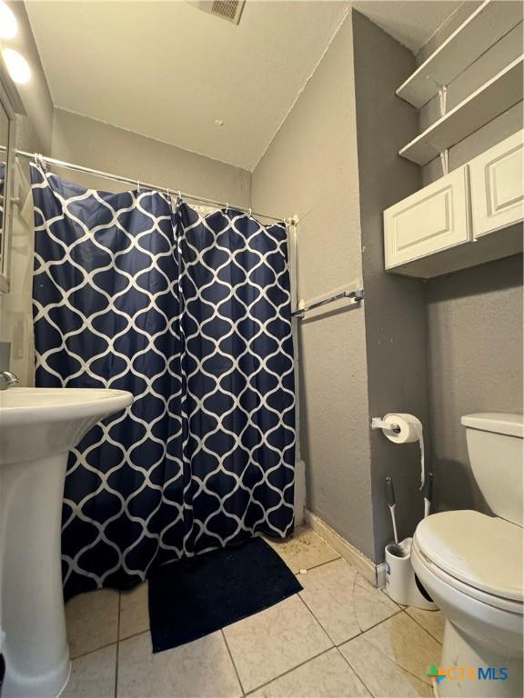 906 N Penelope St, Belton, TX 76513 - full bath featuring tile patterned floors, toilet, and a shower with shower curtain