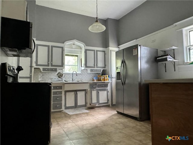906 N Penelope St, Belton, TX 76513 - kitchen featuring stainless steel fridge, backsplash, light countertops, hanging light fixtures, and a sink