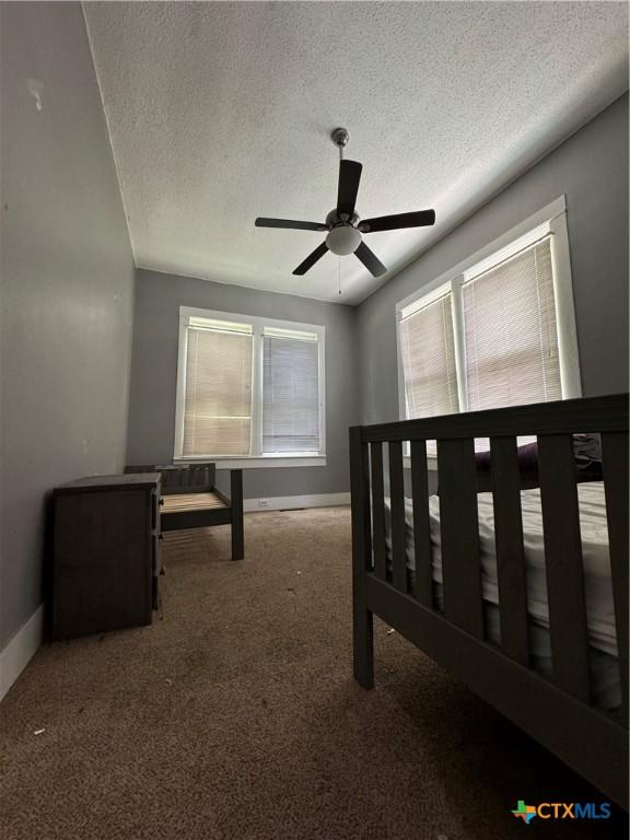 906 N Penelope St, Belton, TX 76513 - unfurnished bedroom featuring baseboards, a textured ceiling, carpet, and ceiling fan