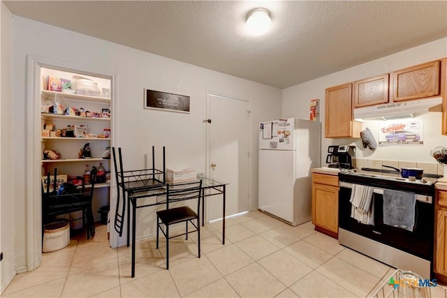 kitchen with a textured ceiling, light tile patterned floors, stainless steel range with electric stovetop, and white refrigerator