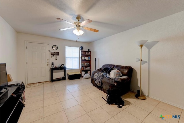 sitting room featuring ceiling fan, light tile patterned floors, and a textured ceiling