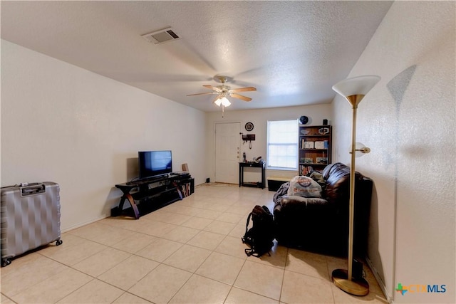 tiled living room with ceiling fan and a textured ceiling