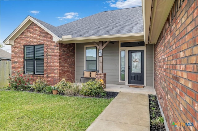 211 Amberglow Ct, Victoria, TX 77904 - property entrance with brick siding, a shingled roof, a lawn, and covered porch