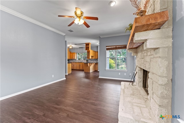 unfurnished living room featuring dark wood-type flooring, ceiling fan, a stone fireplace, and crown molding