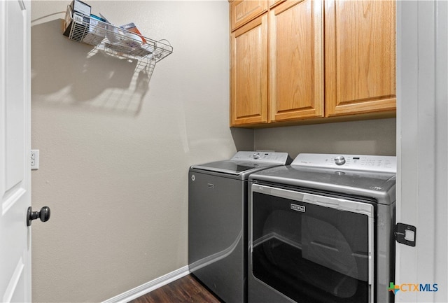 washroom with washing machine and dryer, cabinets, and dark hardwood / wood-style floors