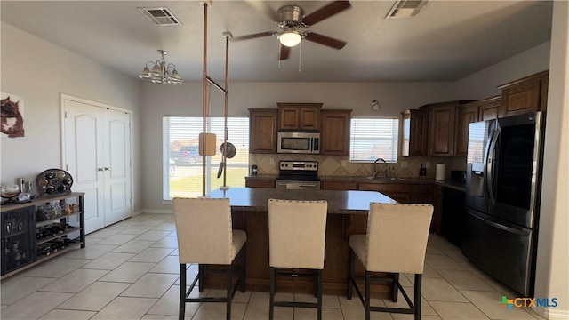 kitchen with a kitchen breakfast bar, sink, appliances with stainless steel finishes, tasteful backsplash, and a kitchen island