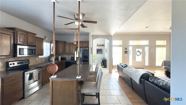 kitchen with a breakfast bar, appliances with stainless steel finishes, a kitchen island, and plenty of natural light