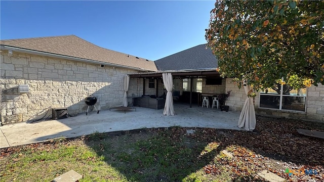 back of house with exterior bar, an outdoor living space, and a patio